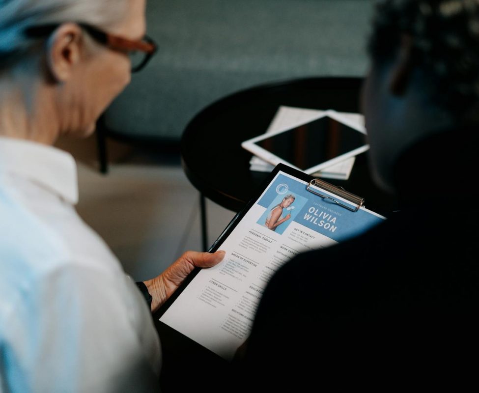 Business professionals conducting an interview with resume on clipboard in an office setting.